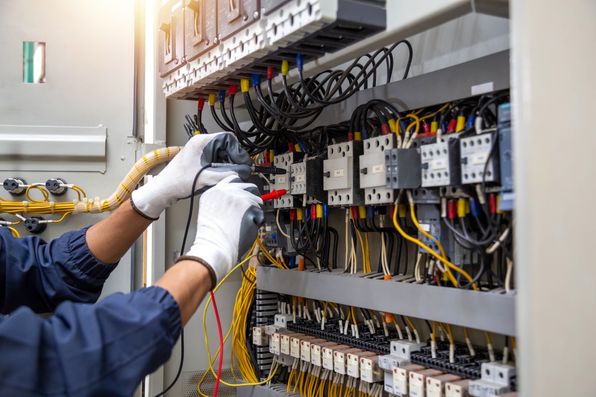 Électricien testant un tableau électrique industriel au multimètre